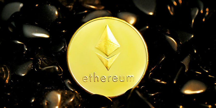 an Ethereum gold coin on top of several black stones